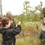 Gordon Tranter from London, England and Blake Wishloff from Devon, AB, pick Saskatoons as Mark Keil holds down a branch.