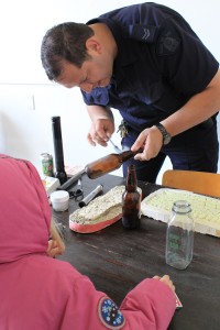 An RCMP officer showing how to remove prints from a bottle at an RCMP open house in 2014.