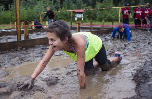 Photo: Evan Matthews Students from McBride & Valemount got down and dirty at the Otway Nordic Ski Club in Prince George last week. Kylie Ilnicki worms her way through the first obstacle with a smile on her face, but she says her favourite portion was swimming at the end. More photos below.