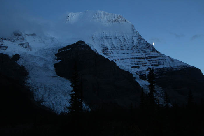 Photo: Dennis Pickerl The peak of Mount Robson makes it's way through the clouds, as the moon creeps around the mountain's side.