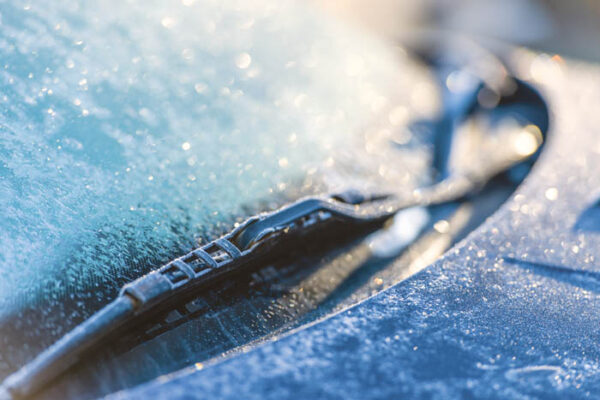 Frozen windshield, cold weather, sunlight on backlight, focus on foreground