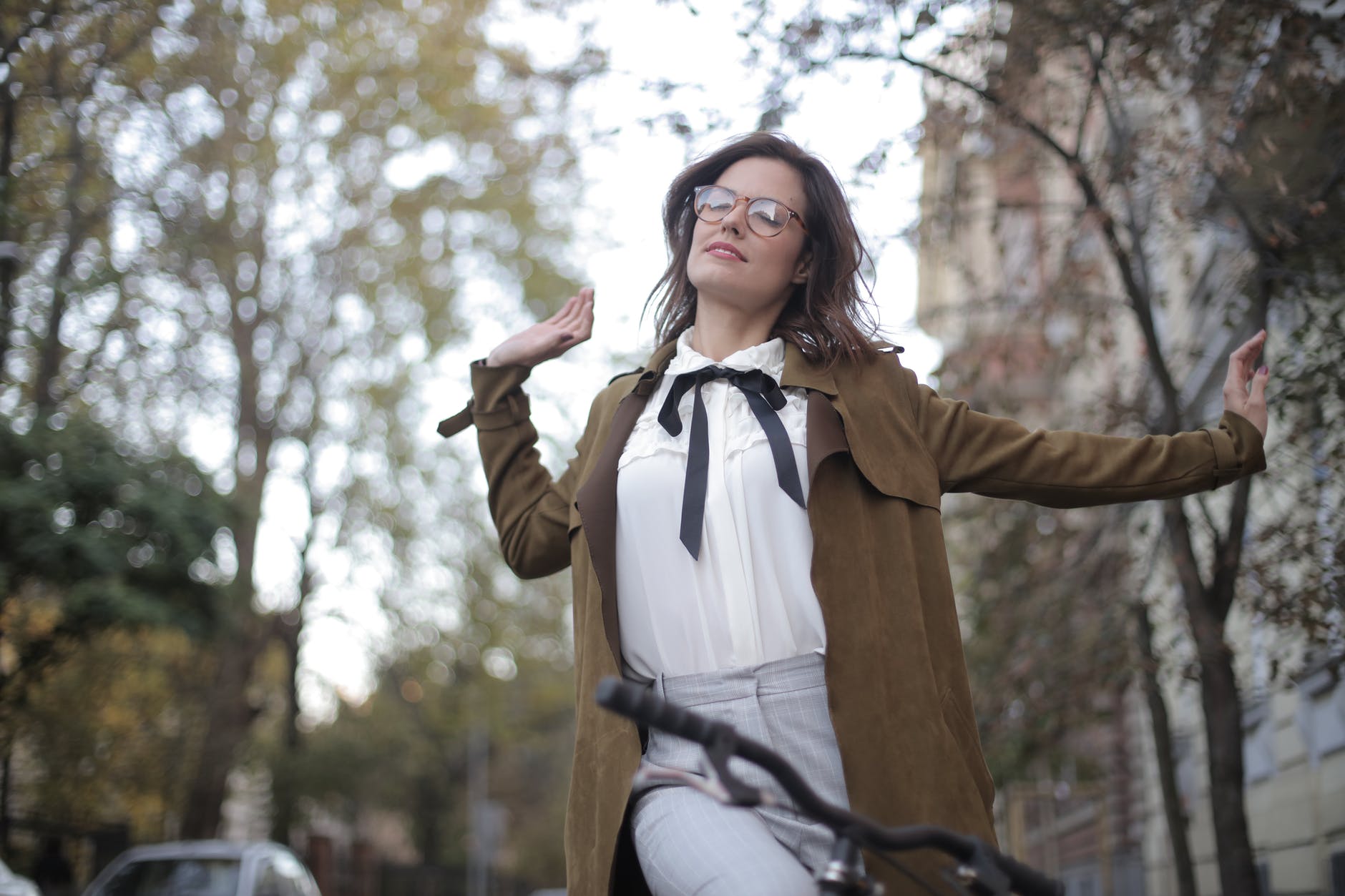 woman in brown blazer riding a bicycle