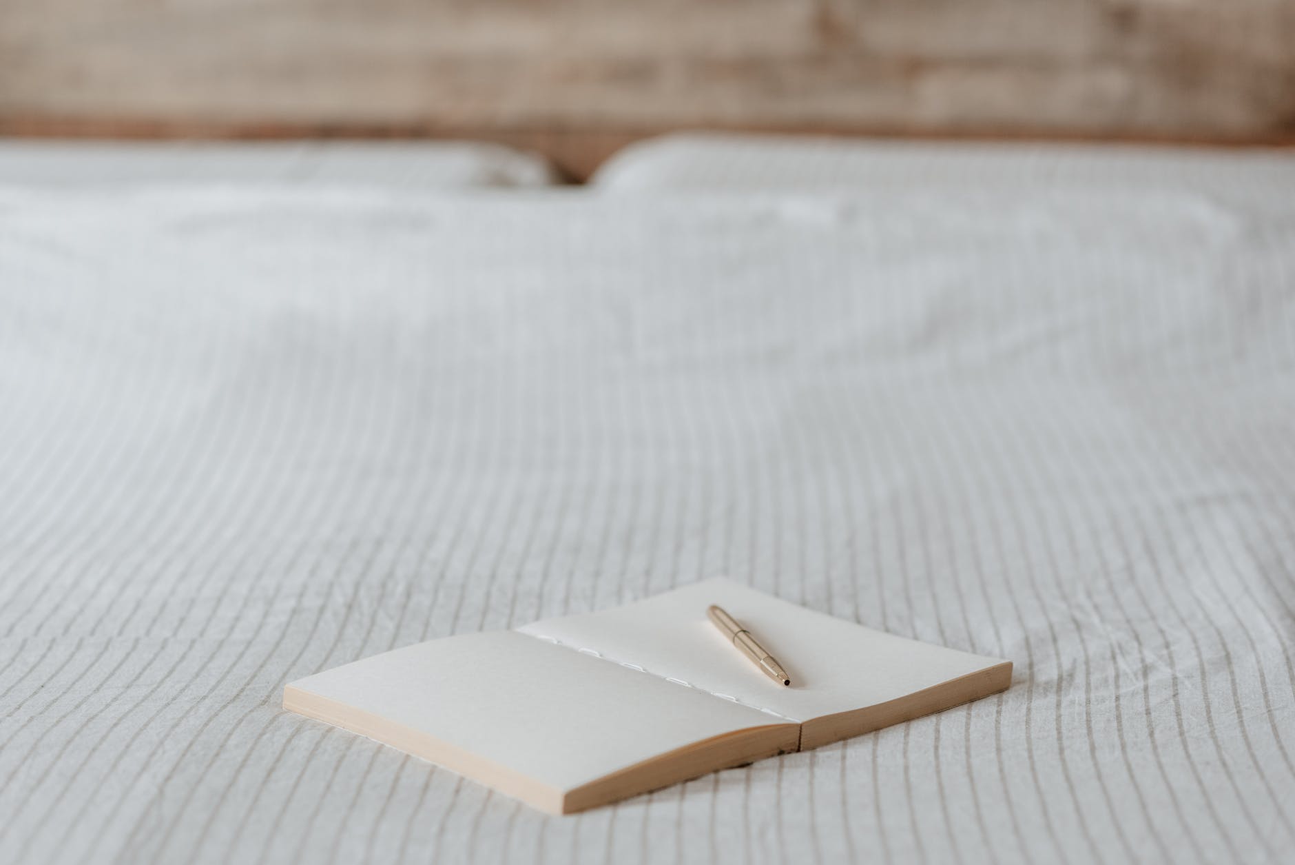 empty agenda with pen on crumpled bed in house